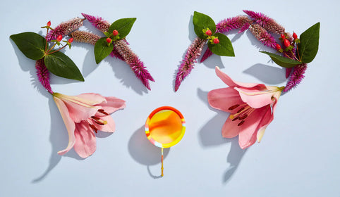 Flowers next to a menstrual disc to represent the tenderness about vaginal flora balancing
