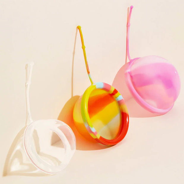Three different sized menstrual discs in three different colors