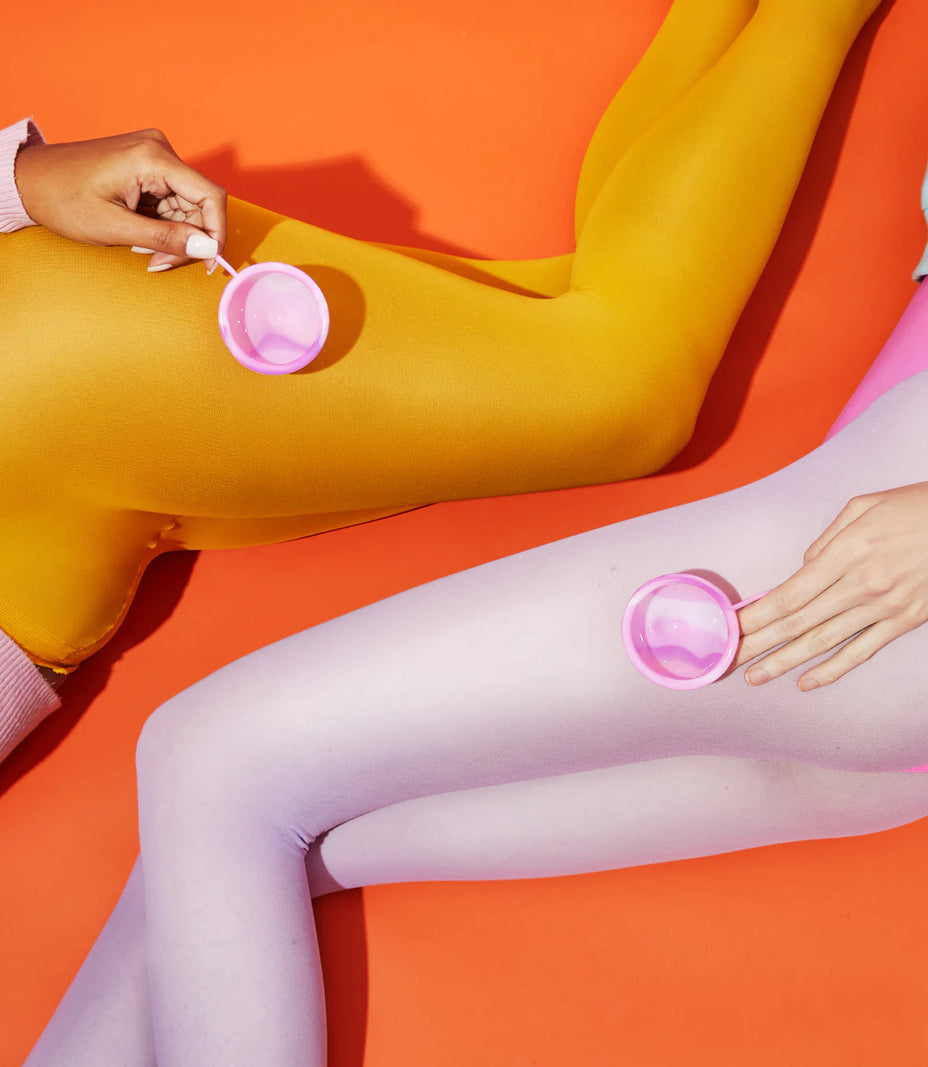 Two people wearing colorful tights with menstrual discs on an orange background